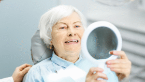 Female patient receiving dental implant treatment at North Down Dental in Bangor, Northern Ireland, smiling in mirror while checking her new teeth.
